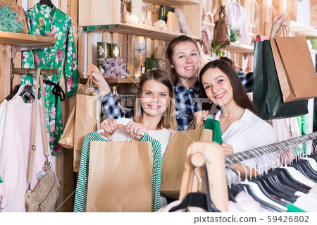 Smiling young women friends carrying paper bags and clothes Smiling young women friends carrying paper bags and clothes 59426802