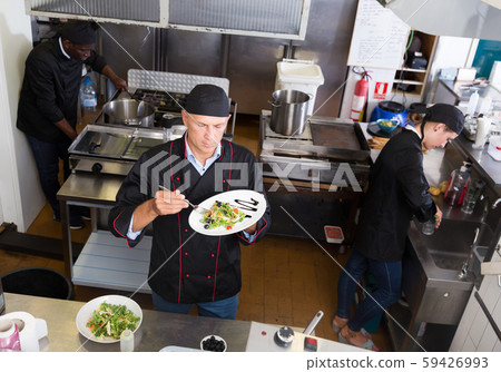 Chef checking dishes in kitchen Chef checking dishes in kitchen 59426993