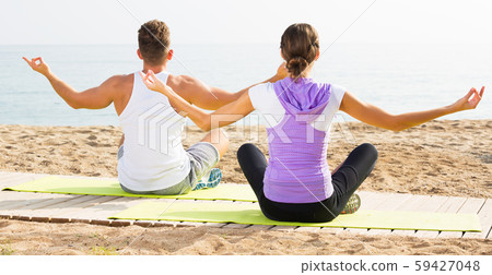 Couple training yoga on beach 59427048