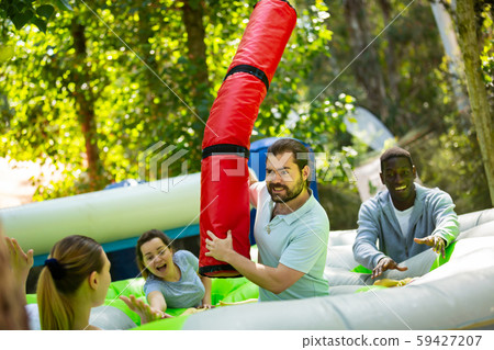 Team of friends playing with inflatable sticks on the trampoline 59427207