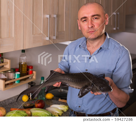Ordinary man standing holding uncooked sturgeon 59427286