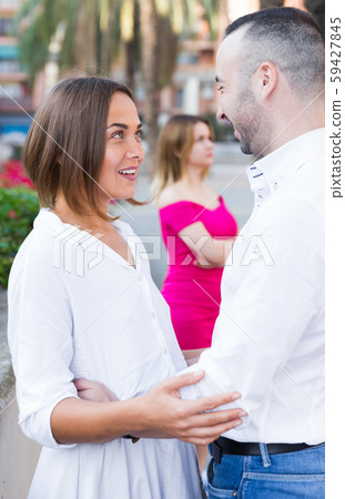 Cheerful couple are talking and woman is envying them Cheerful couple are talking and woman is envying them 59427845