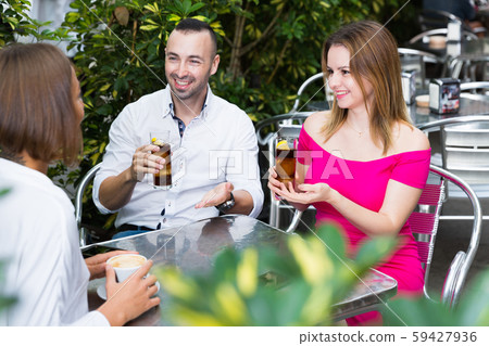 Three friends are drinking coctails and talking Three friends are drinking coctails and talking 59427936