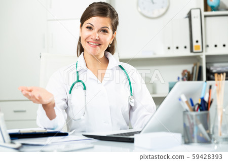 Cheetful woman doctor sitting at workplace with computer in her office 59428393