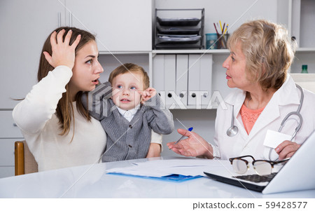Puzzled woman is listening woman doctor about diagnosis her son Puzzled woman is listening woman doctor about diagnosis her son 59428577