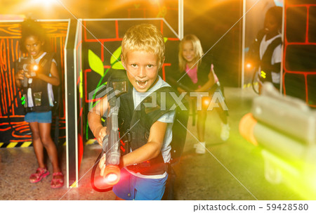 Excited little boy aiming laser gun at other players during lase Excited little boy aiming laser gun at other players during lase 59428580
