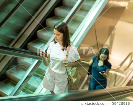 Young women climb the escalator from the subway Young women climb the escalator from the subway 59428916