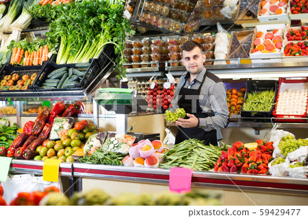 Male shop assistant is weighing grapes Male shop assistant is weighing grapes 59429477