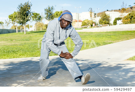 Athletic african american male performs warm-up exercises in park Athletic african american male performs warm-up exercises in park 59429497
