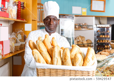 Fine African American baker holding baguettes Fine African American baker holding baguettes 59429547