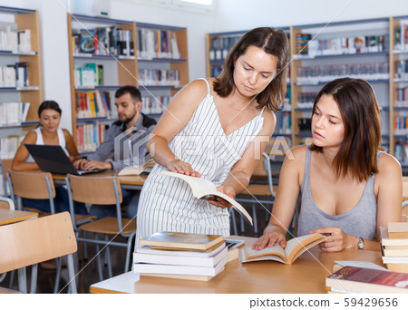 Woman student sitting in university library, working with her teacher 59429656