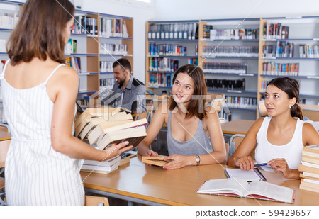 Female students taking books brought by librarian Female students taking books brought by librarian 59429657