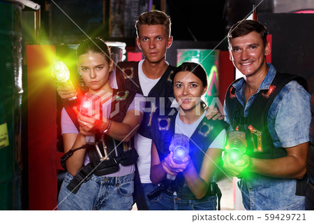 Young girls and guy standing with laser guns during laser tag ga 59429721