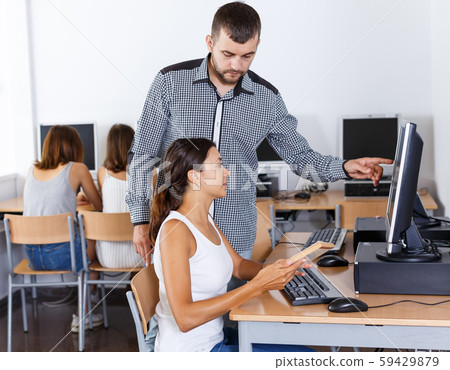 Teacher helping female student in computer class 59429879