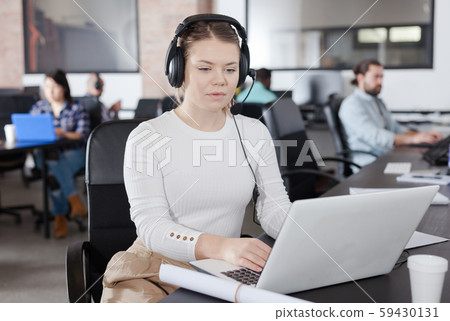 Focused woman in headphones working on laptop 59430131