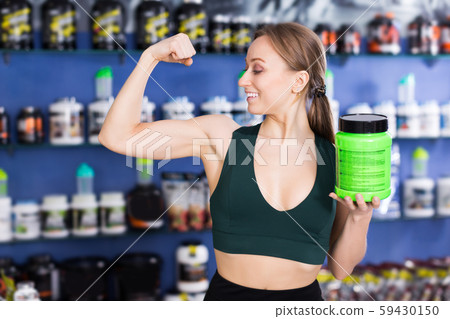athletic girl of sport food supplements showing biceps 59430150