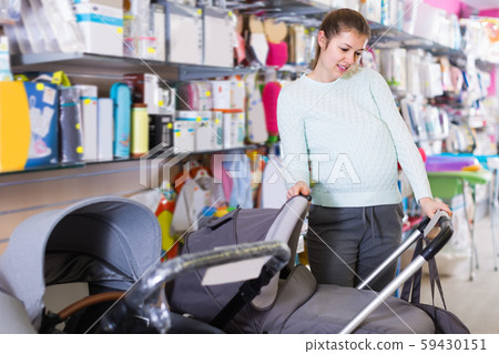 attentive pregnant female is buying carriage for baby in the store 59430151