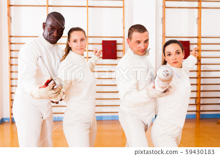 Men and women fencers posing with foils together at fencing workout Men and women fencers posing with foils together at fencing workout 59430183