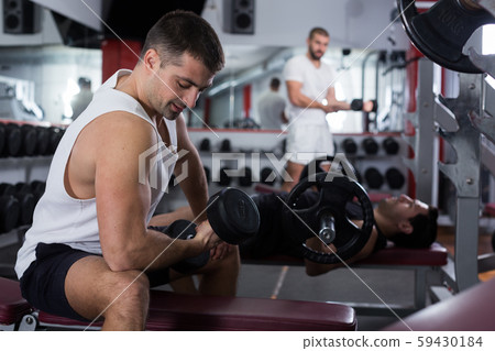 Guy during workout in gym with dumbbells 59430184