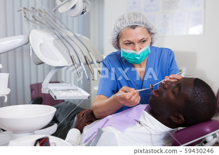 Dentist professional filling teeth for man patient sitting in medical chair 59430246