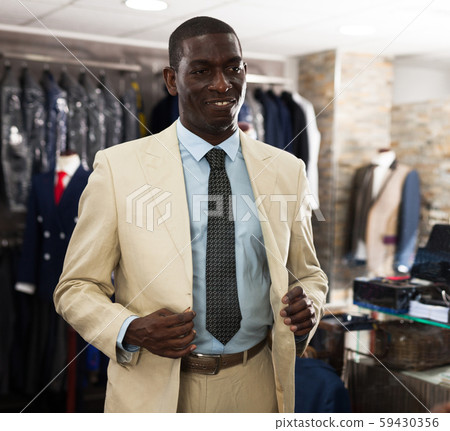 Portrait of male client choosing classic beige jacket in the mall 59430356