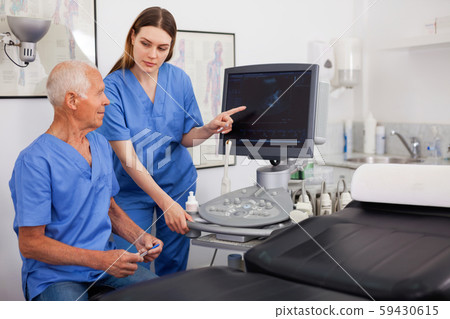 Portrait of young technician showing new ultrasound scan to doct 59430615