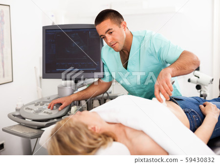 Young man sonographer using ultrasonography machine checking female patient in hospital diagnostic room Young man sonographer using ultrasonography machine checking female patient in hospital diagnostic room 59430832