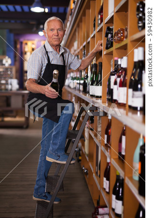Male vintner holding out bottle of wine Male vintner holding out bottle of wine 59430982