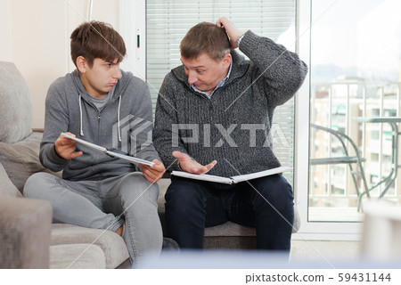 Father and teen son solve school assignment together 59431144