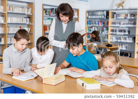 Female librarian and schoolkids during classes in library 59431392