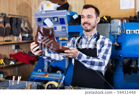 Male worker demonstrating repaired shoes in shoe Male worker demonstrating repaired shoes in shoe 59431448