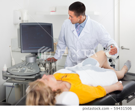 Man during ultrasound test of woman of knee Man during ultrasound test of woman of knee 59431506