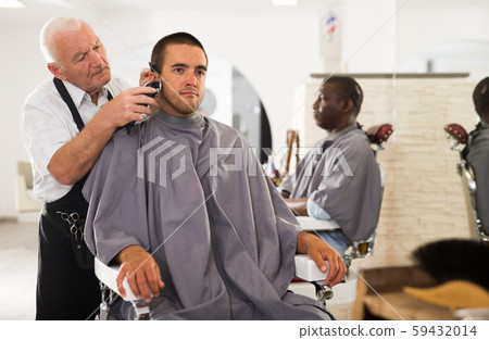 Man getting haircut from aged barber 59432014