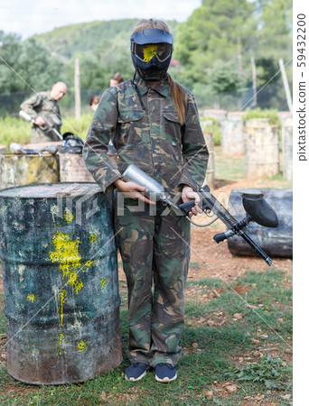 Woman paintball player in camouflage and black mask with traces of paint 59432200