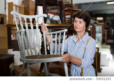 Smiling adult woman is buying antique chair 59432201