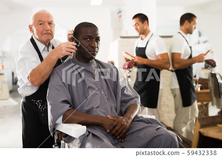 African man getting haircut from elderly barber African man getting haircut from elderly barber 59432338