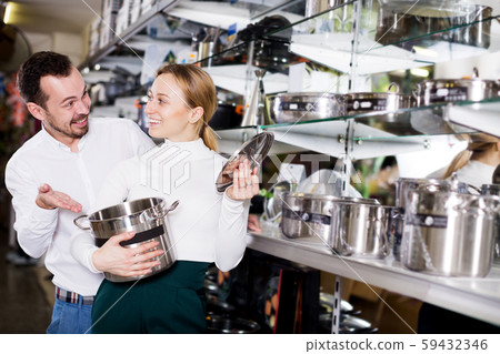Couple examining various saucepans in dinnerware store Couple examining various saucepans in dinnerware store 59432346