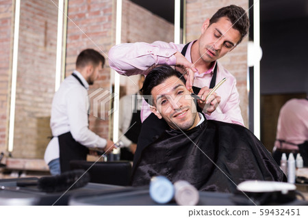 Male getting shave with straight razor in salon 59432451