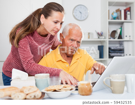 Mature man working at laptop, daughter trying to help him Mature man working at laptop, daughter trying to help him 59432535