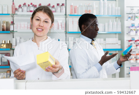 Female pharmaceutist showing medicines in pharmacy Female pharmaceutist showing medicines in pharmacy 59432667