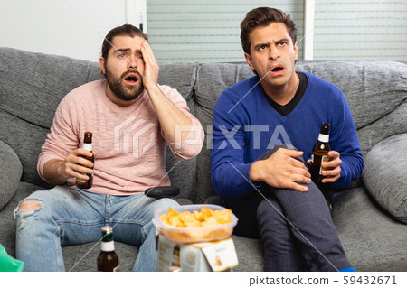 Men drink beer and watch the match on TV 59432671