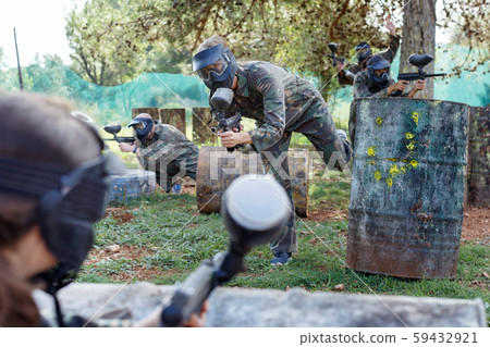Team of adult people playing paintball on battlefield outdoor, running with guns Team of adult people playing paintball on battlefield outdoor, running with guns 59432921