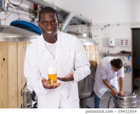 African american man brewer is standing with glass of beer 59432954