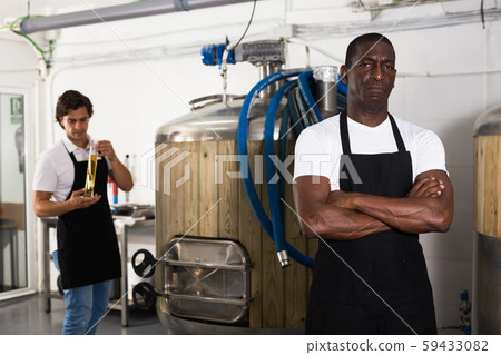 Serious man brewer standing in beer factory during work Serious man brewer standing in beer factory during work 59433082