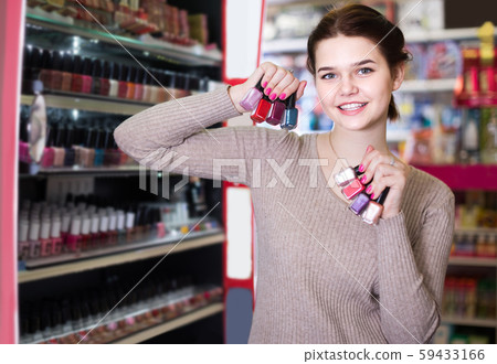 female customer looking for nail polish in cosmetics shop 59433166