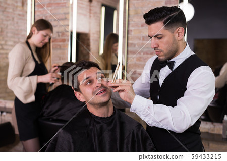 Male getting shave with straight razor in salon 59433215