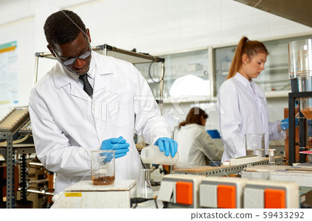 Focused male lab scientist in glasses working with different reagents Focused male lab scientist in glasses working with different reagents 59433292