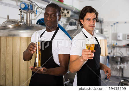 Two professional brewers showing glass and flask of beer Two professional brewers showing glass and flask of beer 59433399