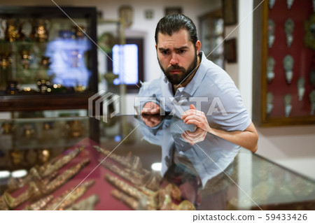 Adult man looking at exhibits in glazed stands in historical museum Adult man looking at exhibits in glazed stands in historical museum 59433426