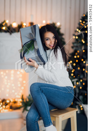 Happy girl in excitement opening Christmas box trying to guess what is inside. Excited woman Happy girl in excitement opening Christmas box trying to guess what is inside. Excited woman 59433432